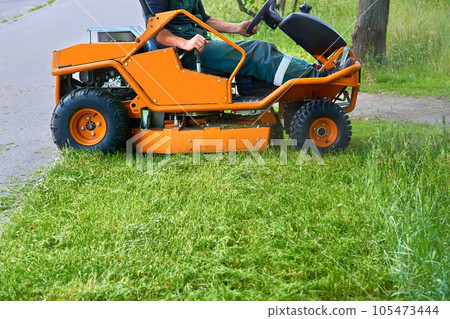 Professional grass cutting on lawns with a mini tractor lawn mower. 105473444