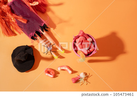 Doll with red hair in a witch costume next to a pink bucket filled with candy 105473461