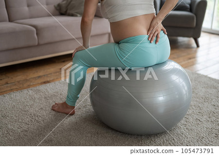 Caucasian pregnant woman suffers from back pain. Fitball training during pregnancy.  105473791