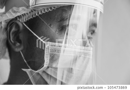 Face of Doctor having tired from work while wearing PPE suit for protect coronavirus disease. Conceptual of health care worker feeling in black and white tone. 105473869
