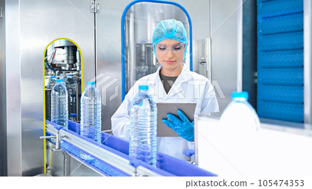 Bottling factory worker inspecting quality of water bottles before shipment. Reverse osmosis system used in plant. water purity and maintaining quality control in bottling process. High quality photo 105474353