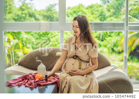 A serene moment captured as a pregnant woman after 40 embraces the soothing benefits of aroma oils and an aroma diffuser, enhancing her pregnancy journey with relaxation and tranquility A serene moment captured as a pregnant woman after 40 embraces the soothing benefits of aroma oils and an aroma diffuser, enhancing her pregnancy journey with relaxation and tranquility 105474492