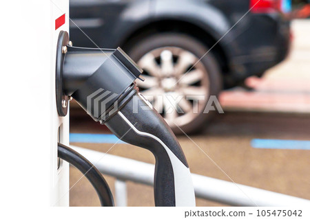 Public electric vehicle charging station with plug close up in car parking Public electric vehicle charging station with plug close up in car parking 105475042