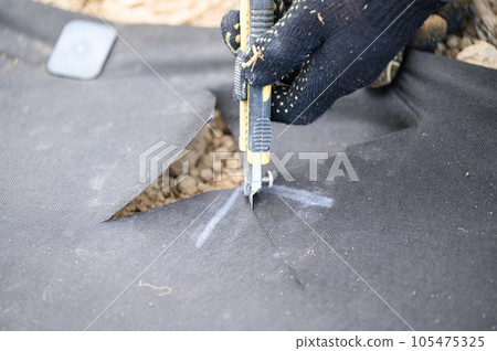 A man cuts a black agricultural fiber along the label A man cuts a black agricultural fiber along the label 105475325