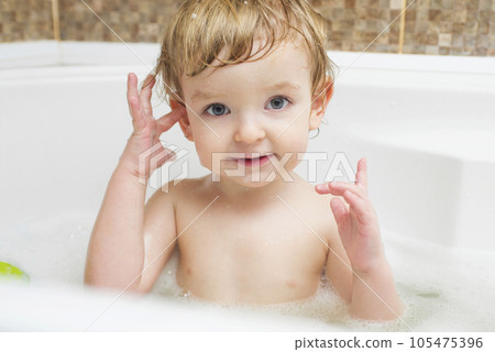 Funny little boy getting a bath in the bathroom.  105475396