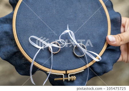 Close-up view of golden wedding rings on blank decorative stiching ring pillow Close-up view of golden wedding rings on blank decorative stiching ring pillow 105475725