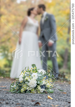 Wedding bouquet on foreground of a blurred kissing couple. Flowers and lovers 105475780
