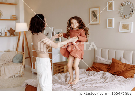 Happy mom and daughter jumping on the bed 105475892