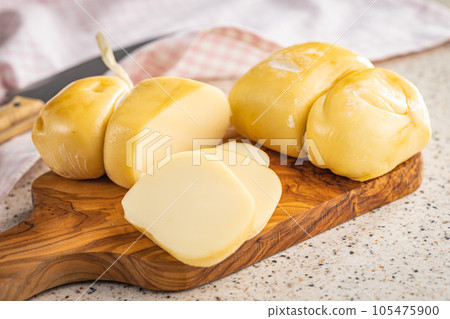 Smoked scamorza cheese on cutting board. 105475900