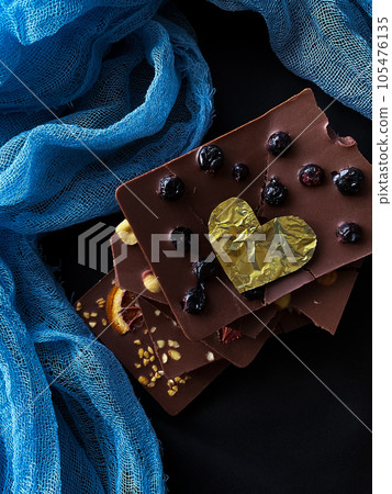 Pieces of chocolate with golden foil heart. With berries, strawberries, oranges Pieces of chocolate with golden foil heart. With berries, strawberries, oranges 105476135