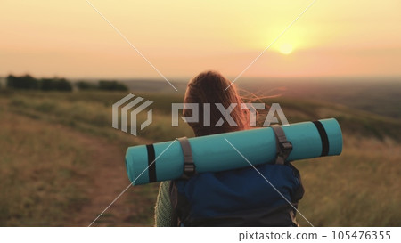 a young girl travels through the mountains at sunset. hiking with travel backpack at sunset. girl with beautiful long hair meets dawn alone. dream young girl travel with backpack hiking. sunset walk. 105476355