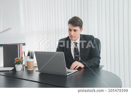 businessman sitting at worktable at modern office analyzing company performance, finance and investment 105478399