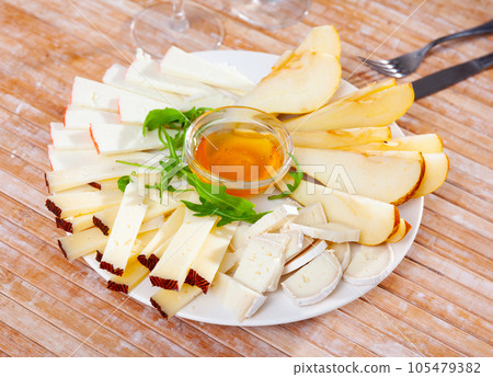 Different types of cheese sliced and served on plate 105479382