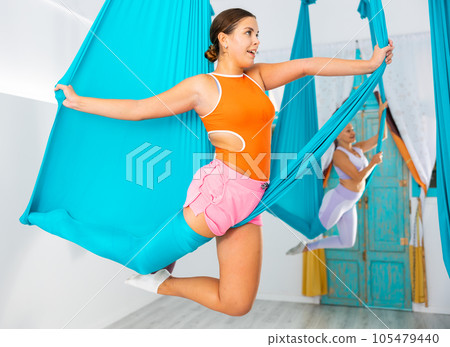 Young women making antigravity yoga exercises with group of people Young women making antigravity yoga exercises with group of people 105479440