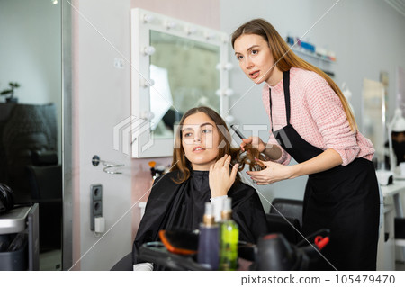 Young woman explains to the hairdresser how she wants to get a haircut Young woman explains to the hairdresser how she wants to get a haircut 105479470