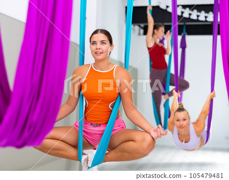Young woman performing antigravity yoga exercise in gym 105479481