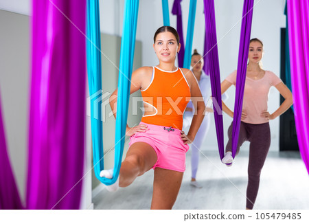 Sporty young girl doing aerial yoga asanas with suspended hammock 105479485
