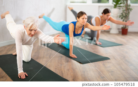 Senior woman standing in balancing asana Dandayamna Bharmanasana 105479518