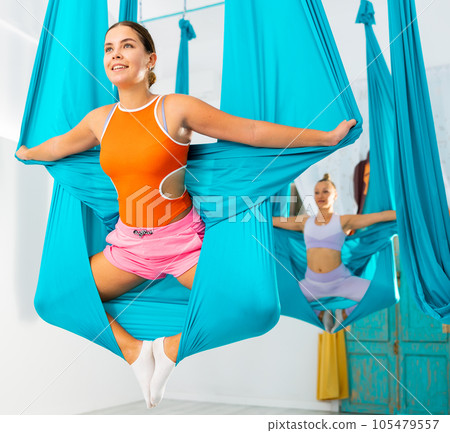 Fit pretty women doing fly yoga stretching exercises in fitness training white gym loft classroom 105479557