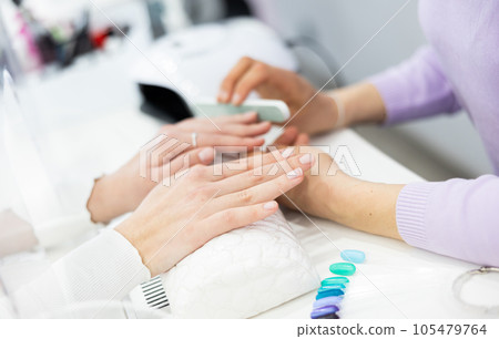 Woman hands, with which the manicure master files nails Woman hands, with which the manicure master files nails 105479764