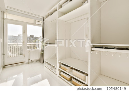 the inside of a room with white walls and shelves on each side, there is an open door that leads to a balcony the inside of a room with white walls and shelves on each side, there is an open door that leads to a balcony 105480149