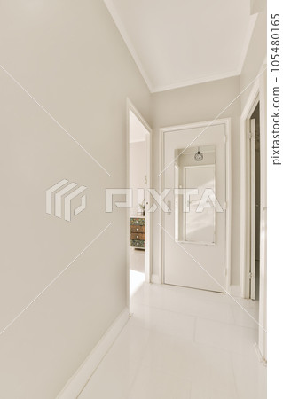 a long hallway with white walls and floor to the right is an open door that leads to another room on the other side 105480165