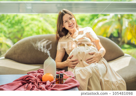 A serene moment captured as a pregnant woman after 40 embraces the soothing benefits of aroma oils and an aroma diffuser, enhancing her pregnancy journey with relaxation and tranquility A serene moment captured as a pregnant woman after 40 embraces the soothing benefits of aroma oils and an aroma diffuser, enhancing her pregnancy journey with relaxation and tranquility 105481098