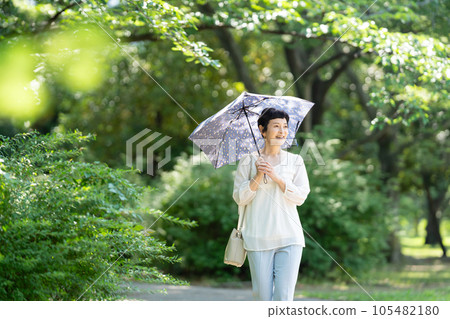A middle-aged woman walking with a parasol 105482180