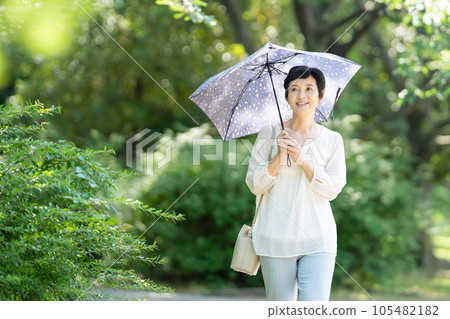 A middle-aged woman walking with a parasol A middle-aged woman walking with a parasol 105482182