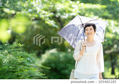 撐著陽傘行走的中年婦女 105482185