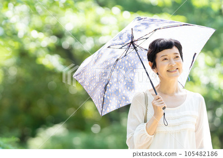 撐著陽傘行走的中年婦女 105482186