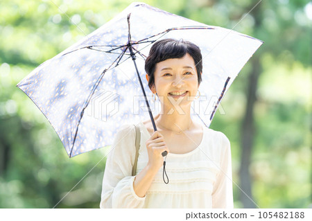撐著陽傘行走的中年婦女 105482188