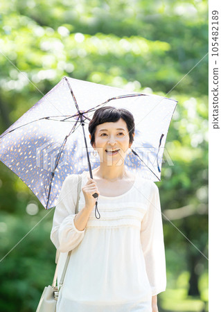 撐著陽傘行走的中年婦女 105482189