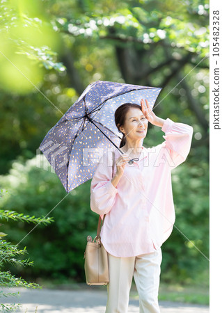 Senior woman walking with a parasol 105482328