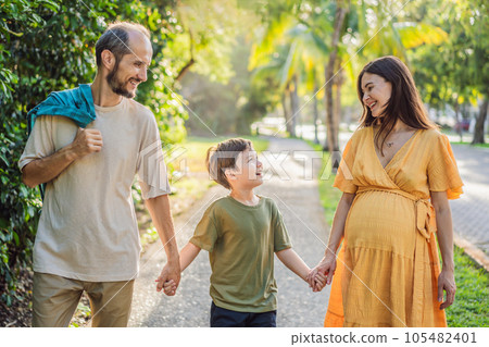A loving family enjoying a leisurely walk in the park - a radiant pregnant woman after 40, embraced by her husband, and accompanied by their adult teenage son, savoring precious moments together A loving family enjoying a leisurely walk in the park - a radiant pregnant woman after 40, embraced by her husband, and accompanied by their adult teenage son, savoring precious moments together 105482401