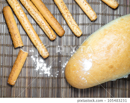 Sesame biscuits and bread on the table. Biscuits are elongated in the form of sticks. Sesame biscuits and bread on the table. Biscuits are elongated in the form of sticks. 105483231