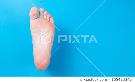 Female bare foot on a blue background.  105483342