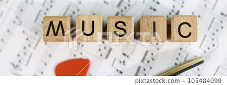 Wooden cubes with letters music and guitar pick on musical notes. 105484099