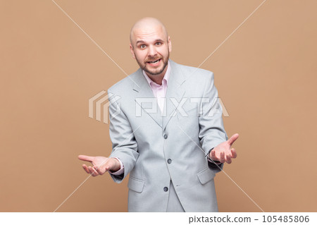 How could you. Portrait of irritated bearded man has problems, gesticulating with hands, crisis and negativity, misunderstanding, wearing gray jacket. Indoor studio shot isolated on brown background. 105485806