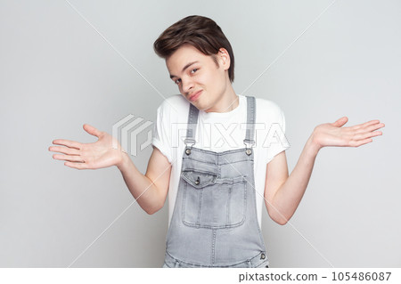 I do not know. Unaware perplexed man spreads palms sideways, has no idea what to do, looks at camera, thinks how to act in troublesome situation. Indoor studio shot isolated on gray background. I do not know. Unaware perplexed man spreads palms sideways, has no idea what to do, looks at camera, thinks how to act in troublesome situation. Indoor studio shot isolated on gray background. 105486087