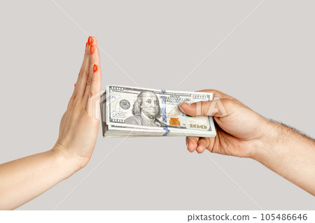 Closeup of woman hand refusing money, man hand offering dollar banknotes, corruption. showing Indoor studio shot isolated on gray background. 105486646