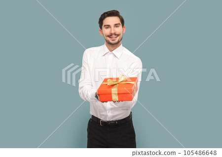 Portrait of friendly positive optimistic man with mustache giving red present box, congratulating with holiday, wearing Indoor studio shot isolated on light blue background. Portrait of friendly positive optimistic man with mustache giving red present box, congratulating with holiday, wearing Indoor studio shot isolated on light blue background. 105486648