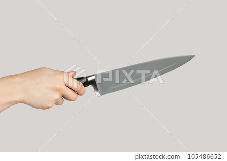 Closeup of woman hand holding huge sharp kitchen knife. Indoor studio shot isolated on gray background. 105486652