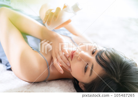Young woman lying down and doing skin care 105487265