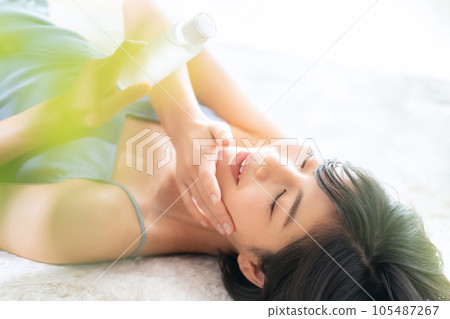 Young woman lying down and doing skin care 105487267