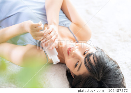 Young woman lying down and doing skin care 105487272