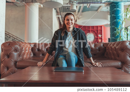 Female freelancer enjoying rest break in co-working space and looking at camera Female freelancer enjoying rest break in co-working space and looking at camera 105489112