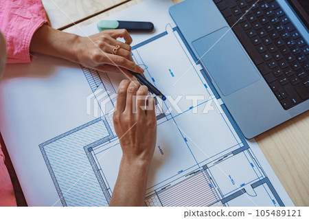 Close up of female architect engineer sketching a construction project with laptop at work place Close up of female architect engineer sketching a construction project with laptop at work place 105489121