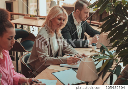 Group of coworkers working together and talking at modern office. Workplace and cooperation concept 105489304