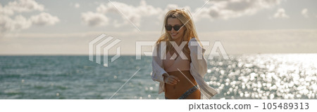 Joyful young woman walking on an empty beach with light falling from the sky 105489313
